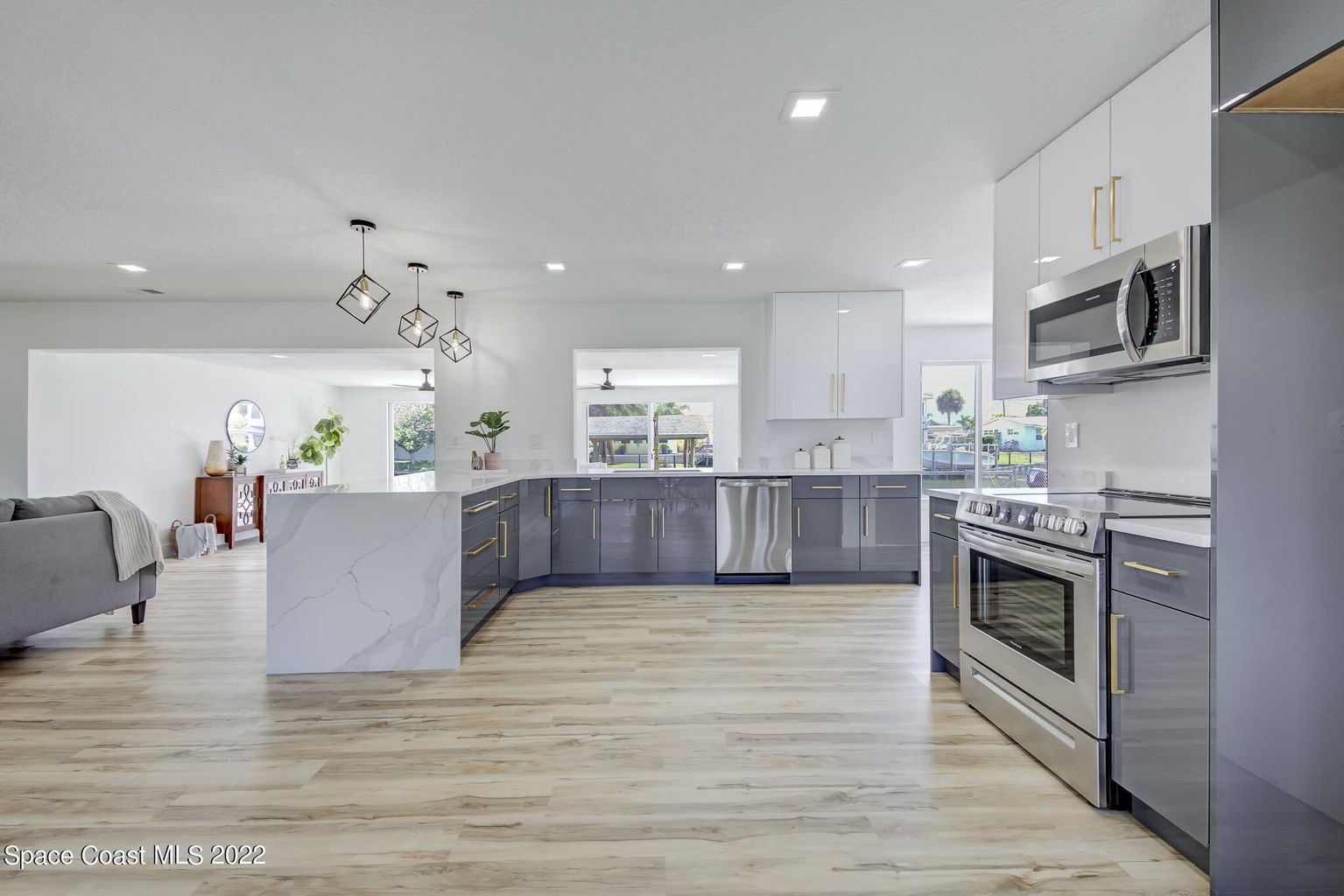 White shaker kitchen with quartz peninsula stainless appliances and herringbone subway tile backsplash by 1 Stop Cabinets