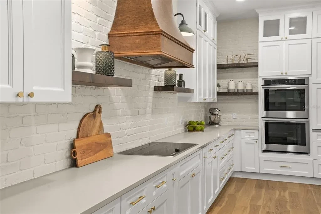 White shaker kitchen with copper range hood and double wall ovens by 1 Stop Cabinets