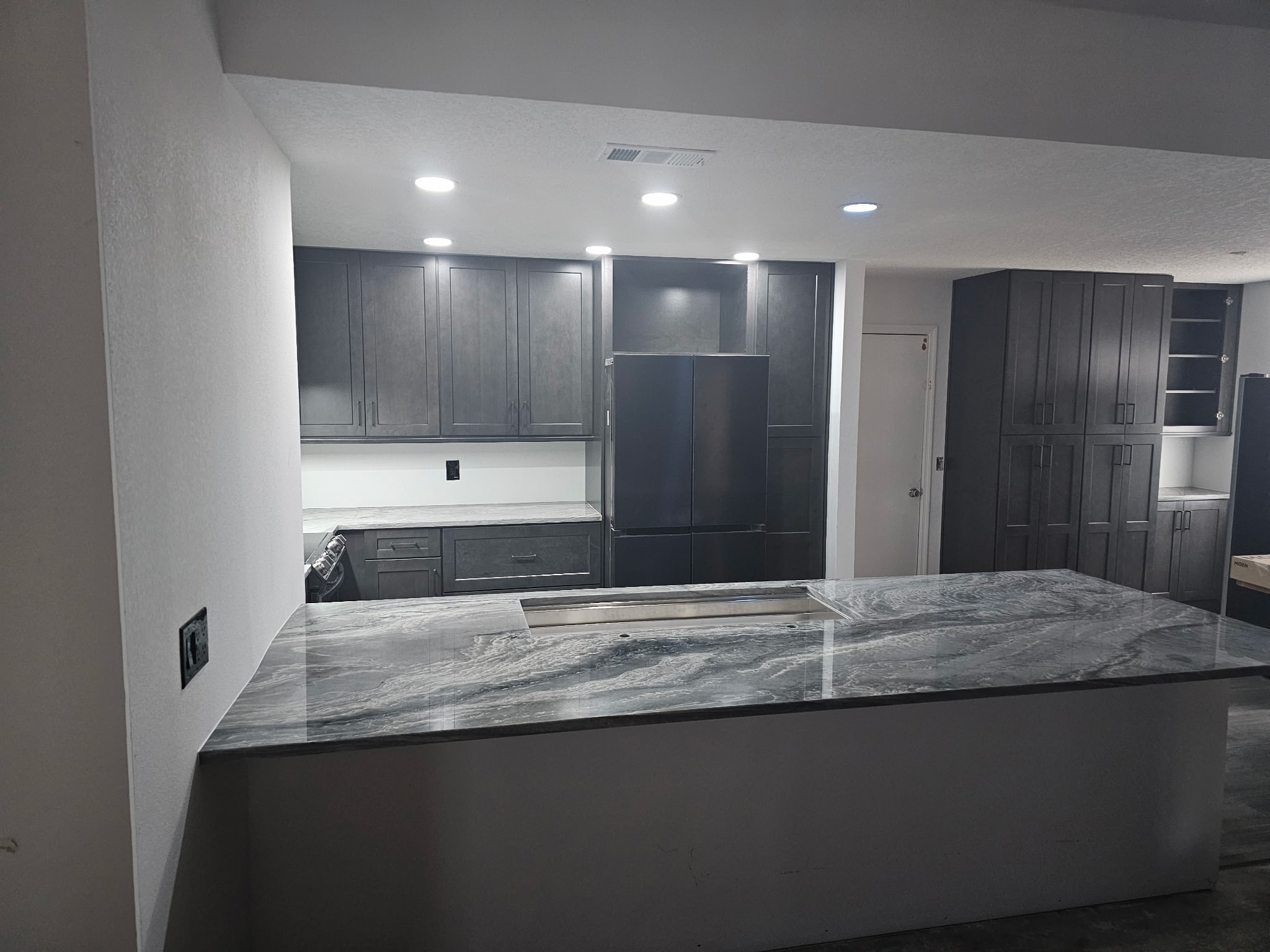 Dark gray shaker kitchen with quartzite island wide view by 1 Stop Cabinets