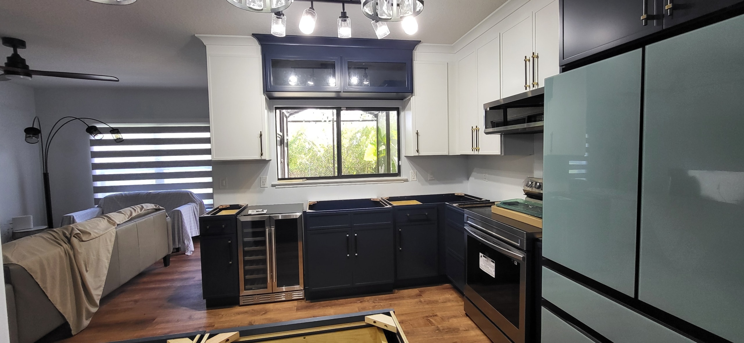 Two-tone navy and white kitchen under construction with wine cooler and glass cabinet doors by 1 Stop Cabinets