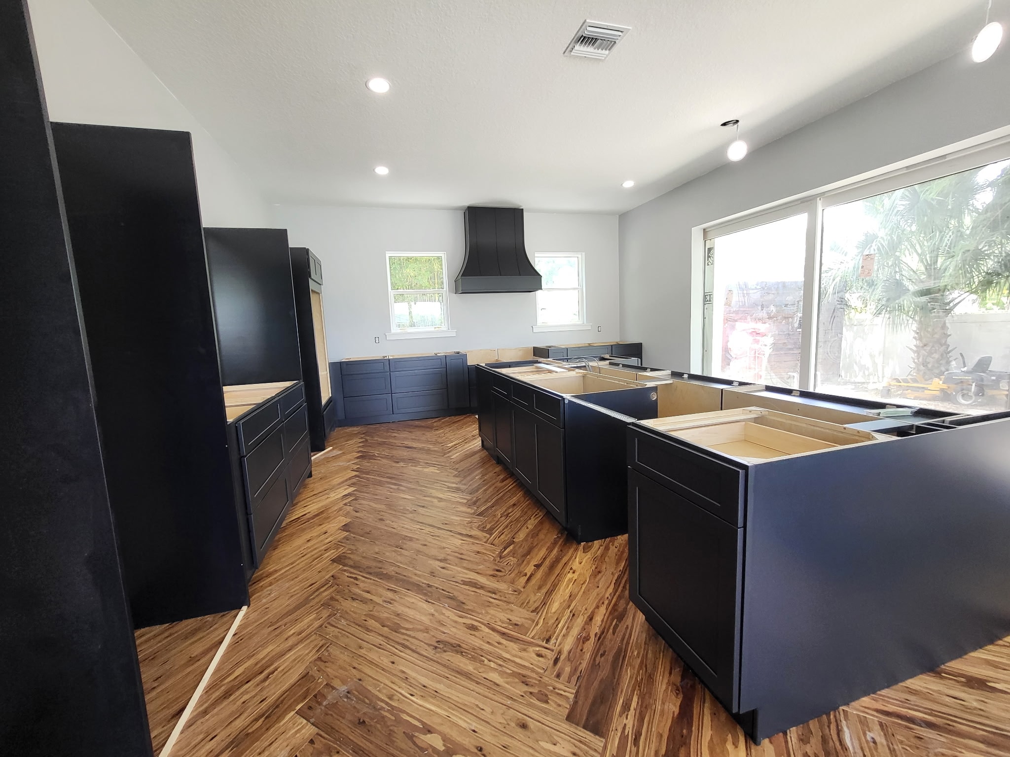 Dark navy shaker kitchen under construction with black range hood and island by 1 Stop Cabinets