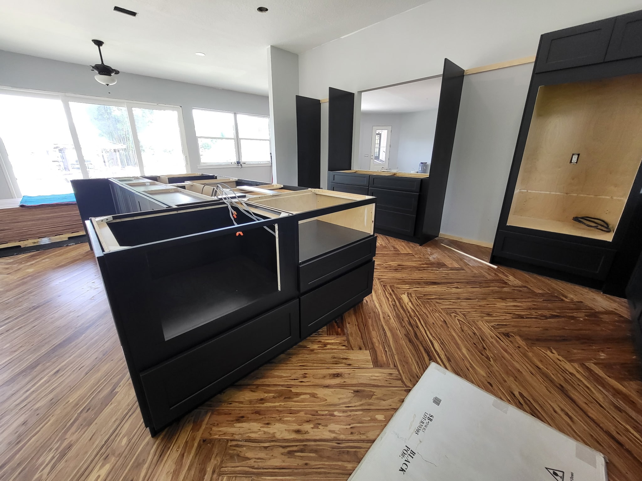 Dark navy shaker kitchen under construction with large island and herringbone floors by 1 Stop Cabinets